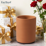 Terracotta utensils holder with gift boxes and red roses on a light background