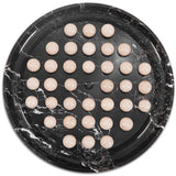 Round black marble board with beige balls on a white background