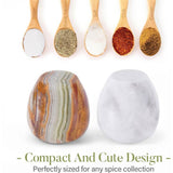 Set of wooden spoons with spices and two decorative salt and pepper shakers on a white background.