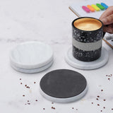 Black speckled mug with a white coaster on a marble surface.