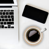 Laptop, smartphone, and coffee cup on a white surface