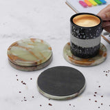 Set of marble coasters on a light surface with a coffee mug.