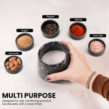 A hand holds a black marble-textured container filled with white salt, surrounded by small labeled bowls of pepper, spices, pink salt, almonds, and sugar on a light surface. Text at the bottom reads 'MULTI PURPOSE' with additional descriptive copy.