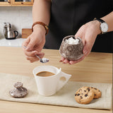 Person adding salt to coffee with cookies on a wooden table