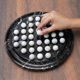 Hand playing with white balls on a black marble-patterned board