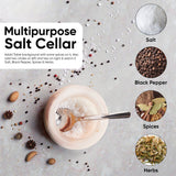 Salt cellar with a spoon on a gray background with salt, black pepper, spices, and herbs.