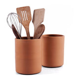 Terracotta utensil holder with wooden kitchen utensils on a white background
