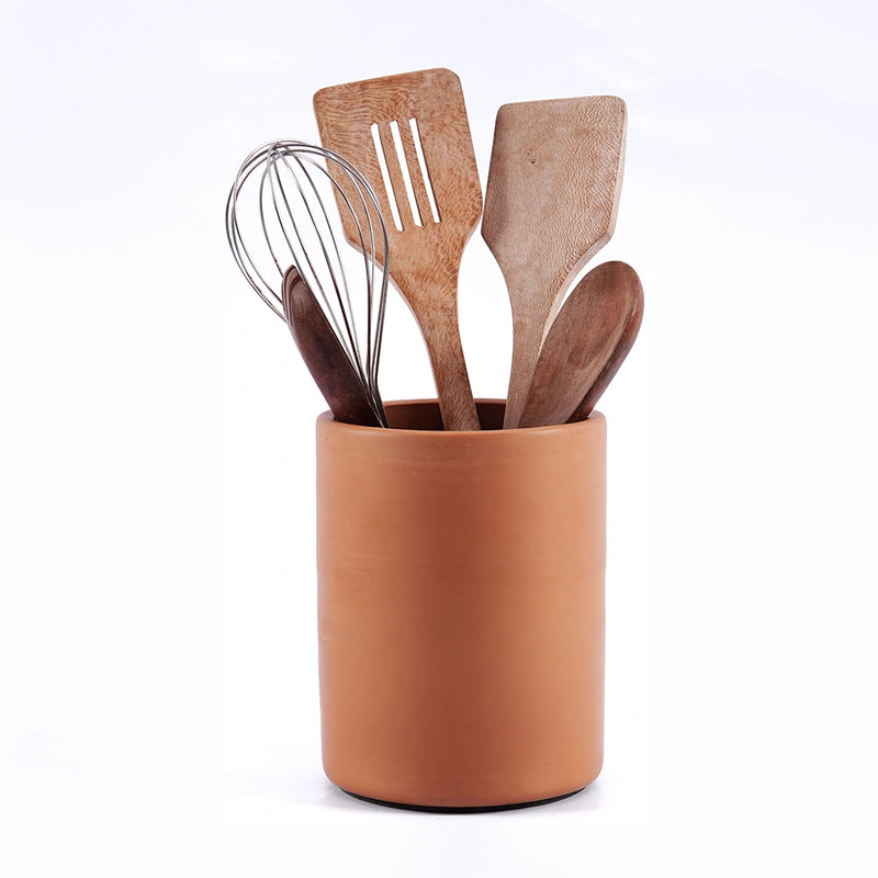 Set of wooden kitchen utensils including a whisk and spatulas in a terracotta-ocontainer on a white background.