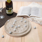 travertine board with marble stones on a wooden table with a bottle of Heaven's Door beer and an open book.